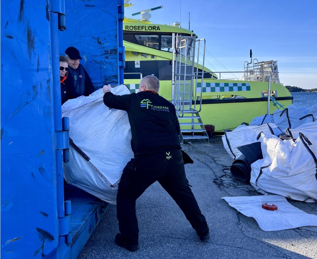 Mann dytter søppel inn i container
